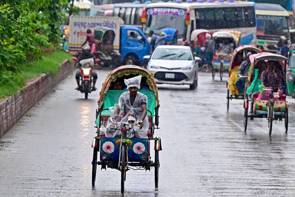 Bangladeshi rickshaw pullers ride along a street, amid rainfall in Dhaka on September 25, 2024. (Photo by MUNIR UZ ZAMAN / AFP)
