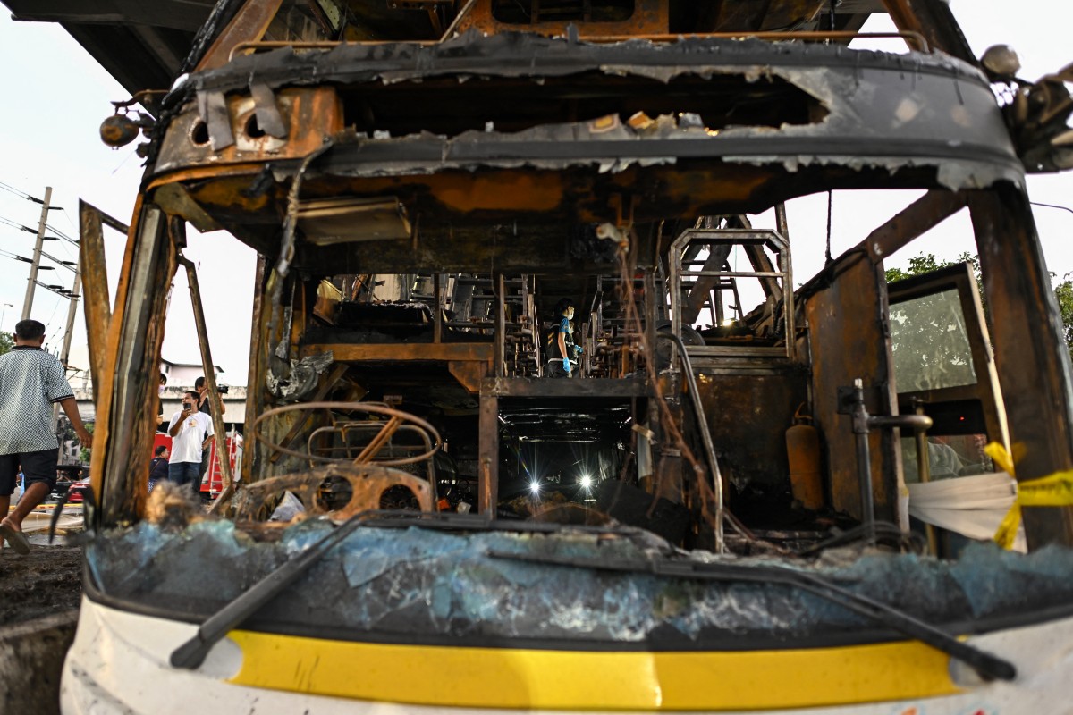 A police officer (C) inspects a burnt-out bus that was carrying students and teachers on the outskirts of Bangkok on October 1, 2024. Photo by Manan VATSYAYANA / AFP