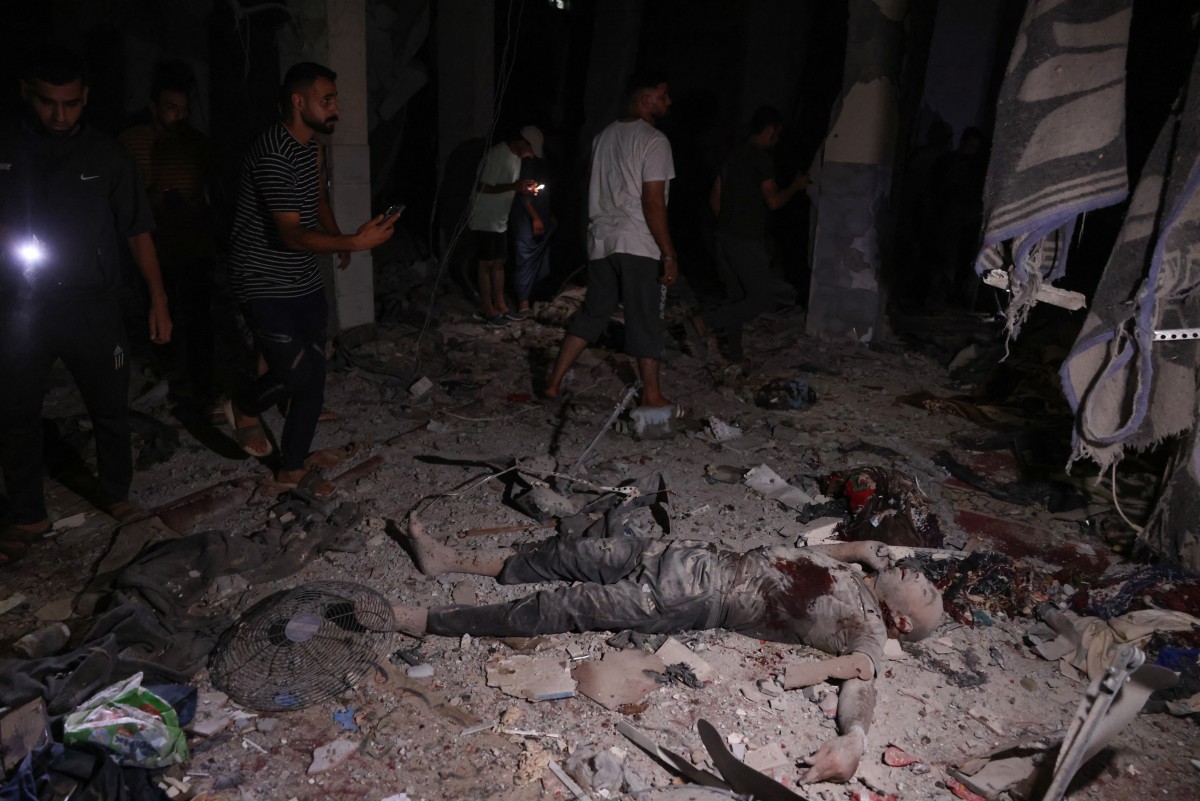 Palestinians use their telephone torches to search for the victims of an Israeli strike that targeted a mosque-turned-shelter in Deir al-Balah in the central Gaza Strip, during the night of October 6, 2024. Photo by BASHAR TALEB / AFP.