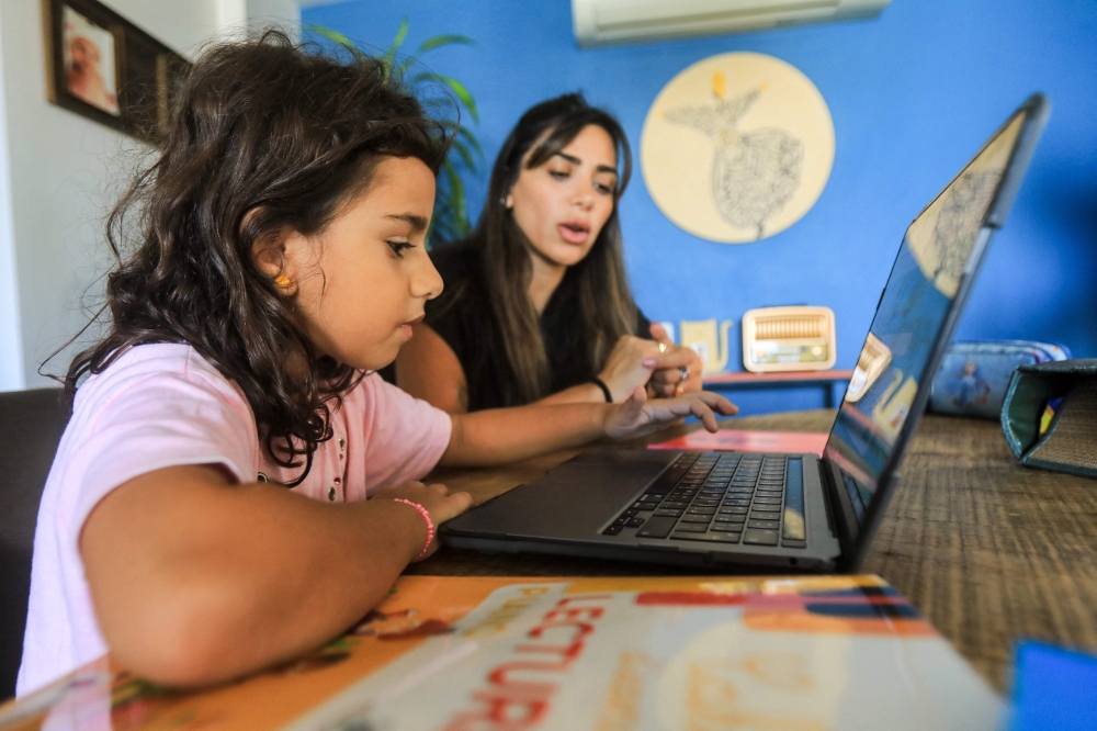 Noor Khawaja, 36, helps her seven-year-old daughter Jude study at their apartment in Beirut on October 5, 2024. Photo by AFP