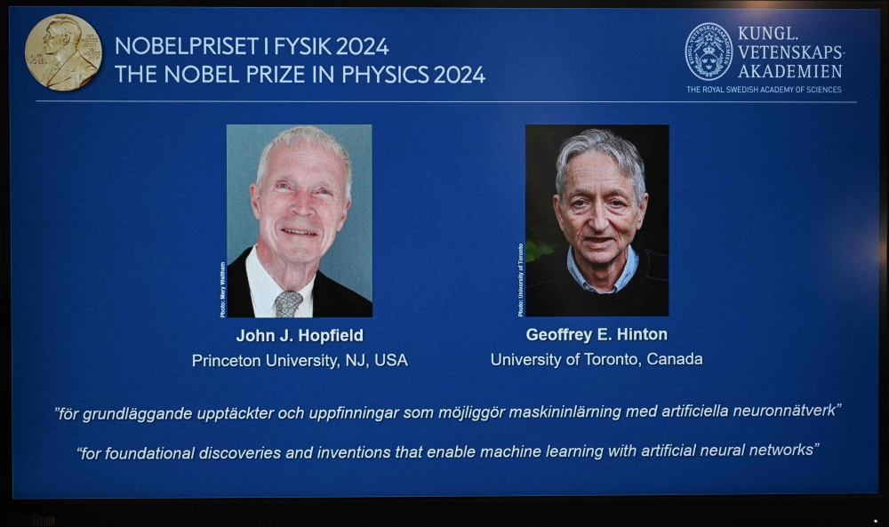 A screen shows the laureats of the 2024 Nobel Prize in Physics, US physicist John J Hopfield and Canadian-British computer scientist and cognitive psychologist Geoffrey E Hinton on October 8, 2024. (Photo by Jonathan Nackstrand / AFP)