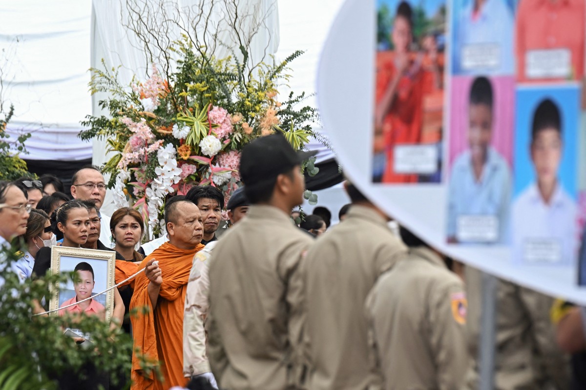 Grieving family members hold portraits of their loved ones during the cremation ceremony for the victims of a school bus fire, which marks the last Buddhist funeral rites at Wat Khao Phraya Sangkharam School in Uthai Thani on October 8, 2024.