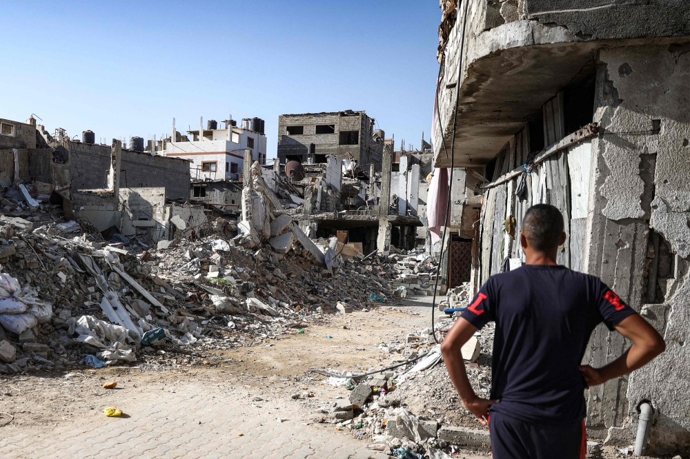 A man stands before a collapsed building in the Bureij camp for Palestinian refugees in the central Gaza Strip on October 9, 2024. (Photo by Eyad Baba / AFP)