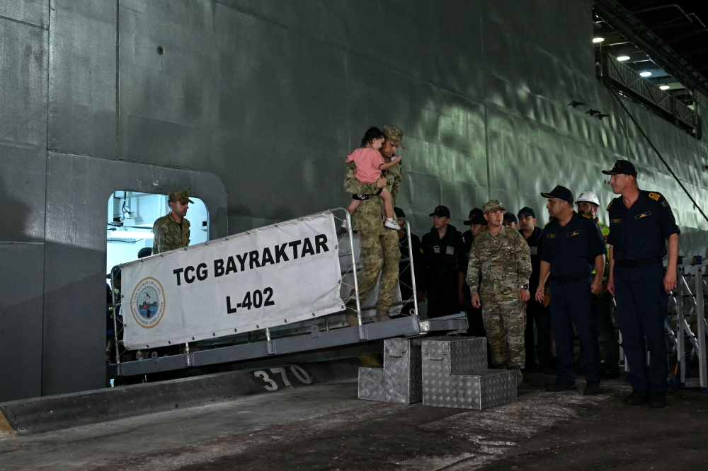 A Turkish soldier holds a child evacuee as Turkish citizens evacuated from Lebanon disembark from the TCG L402 Bayreaktar Turkish war ship after its arrival at the southern Turkish port of Mersin, southern Turkey, on October 10, 2024. (Photo by Ozan Kose / AFP)