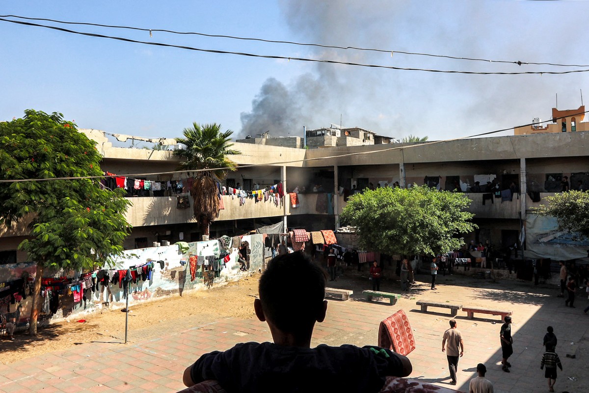 A boy watches a smoke plume rise while standing in the balcony of the Rafei school, being used as a displacement shelter, in the Jabalia camp for Palestinian refugees in the northern Gaza Strip on October 9, 2024. Photo by Omar AL-QATTAA / AFP