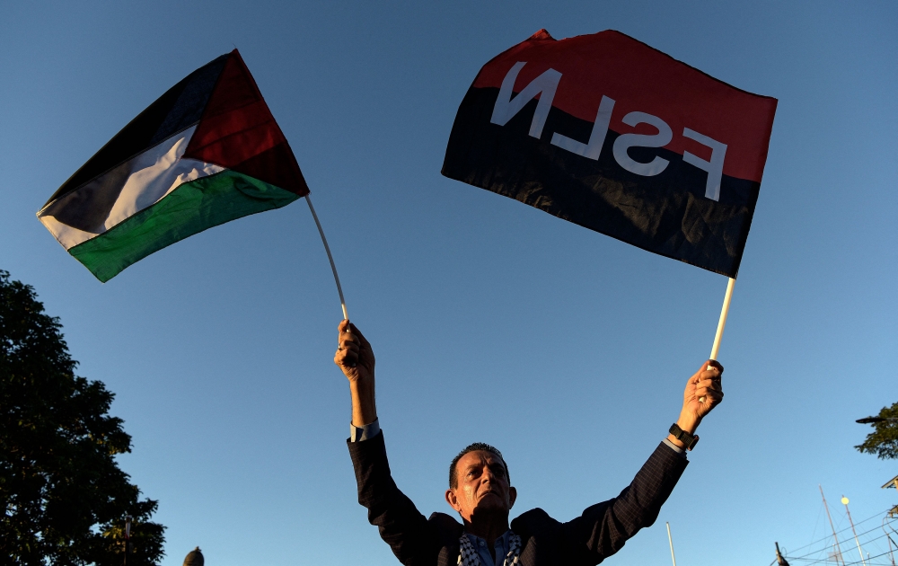 (Files) A man holds a Palestinian and Sandinista flags during the inauguration of Gaza street in support to the Palestinian people, in the historic center of Managua on January 30, 2024. (Photo by Oswaldo Rivas/ AFP)