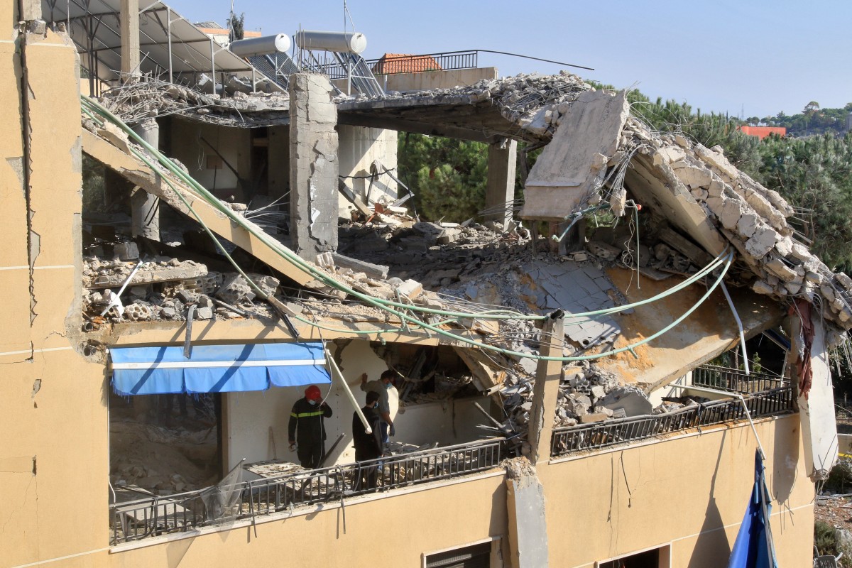 Photo used for demonstration purposes. First responders stand on the balcony of an apartment building that was targeted in an Israeli airstrike in the village of Wardaniye, south of Beirut on October 9, 2024. Photo by Mahmoud ZAYYAT / AFP.
