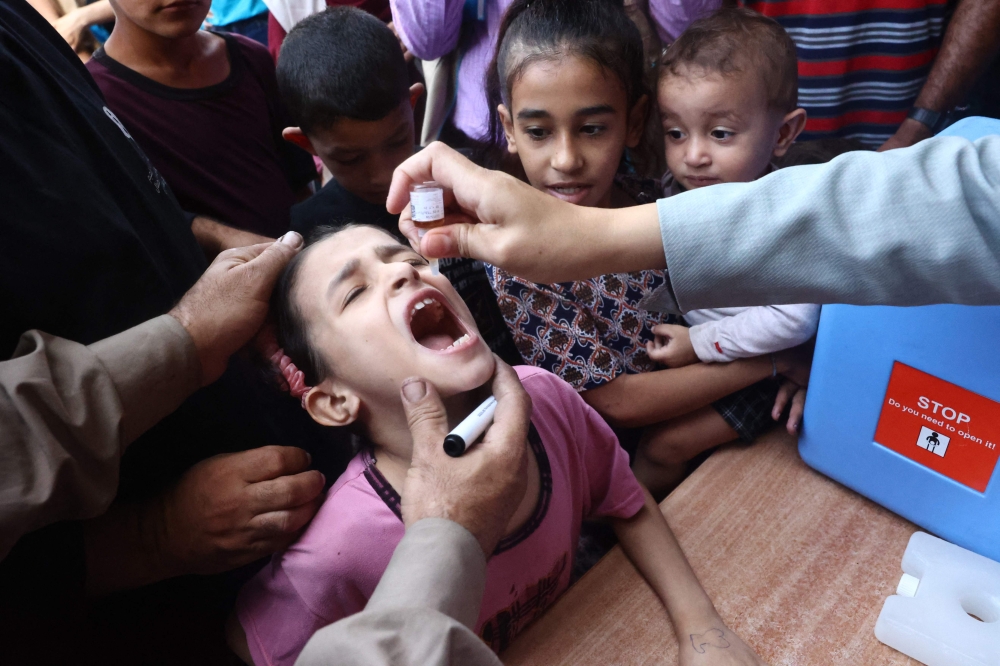 Palestinian children receive drops as part of a polio vaccination campaign in Deir al-Balah in the central Gaza Strip on October 14, 2024. Photo by Eyad BABA / AFP