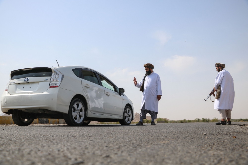 Taliban members of the Ministry for Propagation of Virtue and Prevention of Vice inspect vehicles at a checkpoint along a road on the outskirts of Herat province on October 4, 2024. (Photo by Mohsen Karimi / AFP)