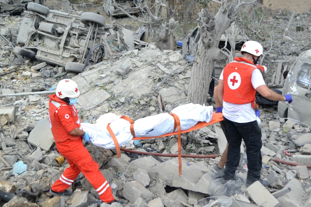 Paramedics with the Lebanese Red Cross transport a body unearthed from the rubble at the site of an Israeli airstrike that targeted the northern Lebanese village of Aito on October 14, 2024. (Photo by Fathi Al-MasriI / AFP)