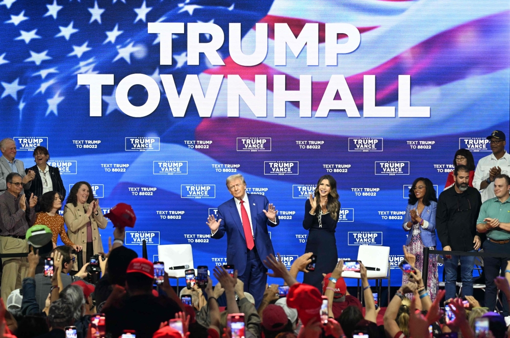 Former US President and Republican presidential candidate Donald Trump, with moderator and South Dakota Governor Kristi Noem (right), arrives for a town hall at the Greater Philadelphia Expo Center and Fairgrounds in Oaks, Pennsylvania, on October 14, 2024. (Photo by Jim Watson / AFP)