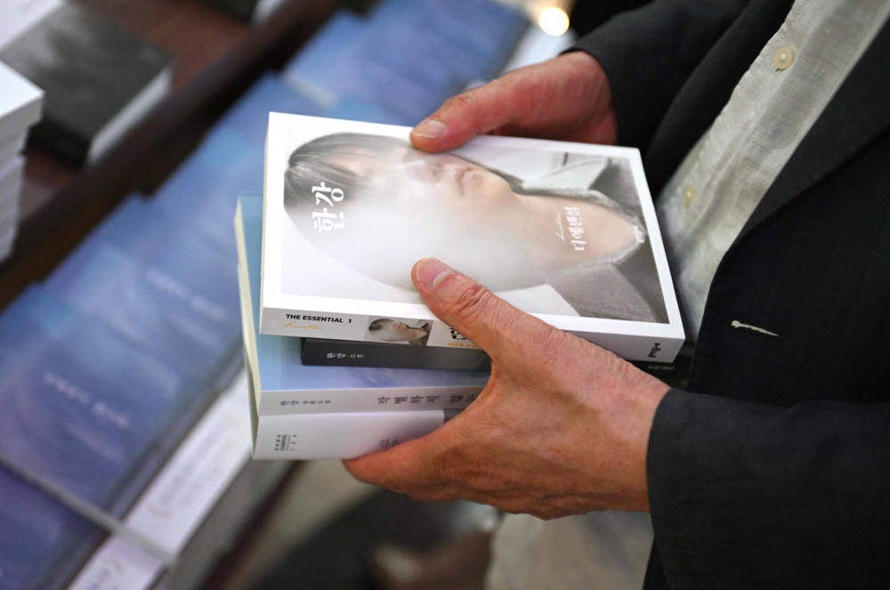 A man holds books by South Korean author Han Kang, who won the 2024 Nobel Prize in Literature, at a bookstore in Seoul on October 11, 2024. Photo by Jung Yeon-je / AFP