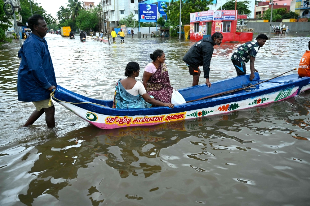 People ride a boat through a flooded street amid heavy rainfall in Chennai on October 16, 2024. (Photo by R.Satish BABU / AFP)