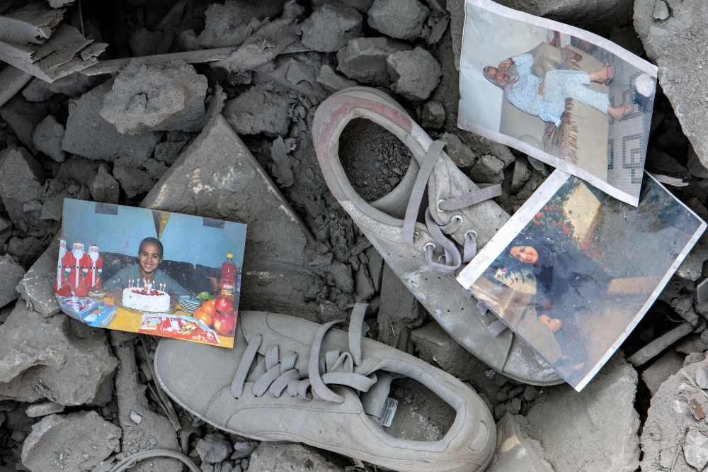 Personal photograph prints and sneaker shoes are strewn through the rubble of a destroyed building in the aftermath of an overnight Israeli air strike on the village of Qana in southern Lebanon on October 16, 2024. (Photo by Bilal Kashmar / AFP)