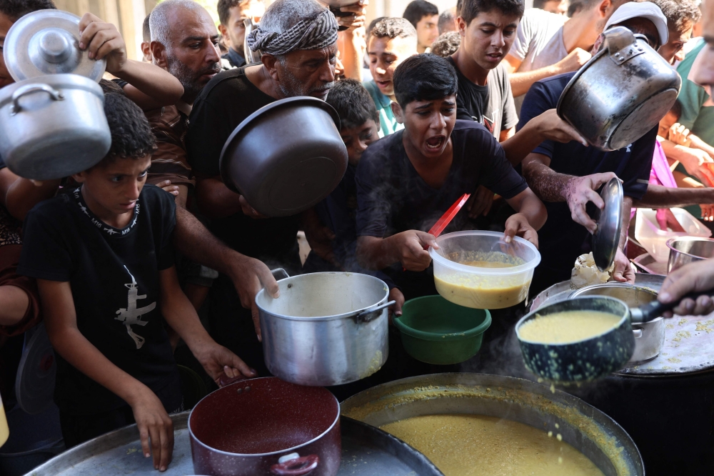 Displaced Palestinians queue to receive food rations, offered by a charity, in Gaza's Al-Shati refugee camp on October 17, 2024. Photo by Omar AL-QATTAA / AFP