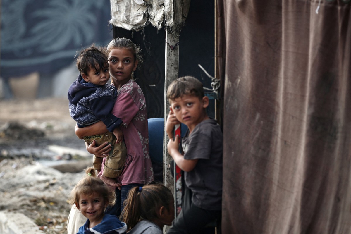 Palestinian children stand next to tents at a make-shift camp for the internally displaced in Deir al-Balah in the central Gaza Strip on October 17, 2024. Photo by Eyad BABA / AFP.
