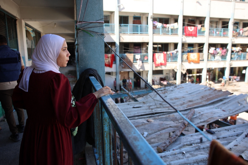 A displaced young Palestinian woman stares from a balcony inside UN school-turned-refuge in the Al-Shati refugee camp near Gaza City in the northern Gaza Strip, following a reported Israeli strike on October 19, 2024. (Photo by Omar Al-Qattaa / AFP)
 