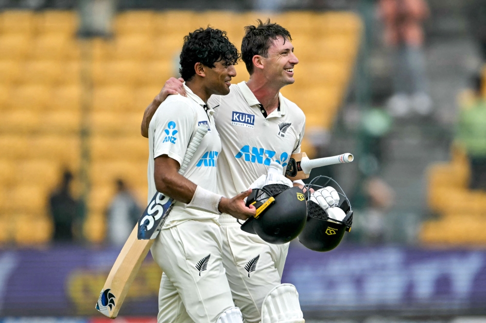 New Zealand's Will Young (R) and Rachin Ravindra celebrate their team's win against India at the end of their first Test cricket match in the M. Chinnaswamy Stadium of Bengaluru on October 20, 2024. (Photo by Idrees Mohammed / AFP) 