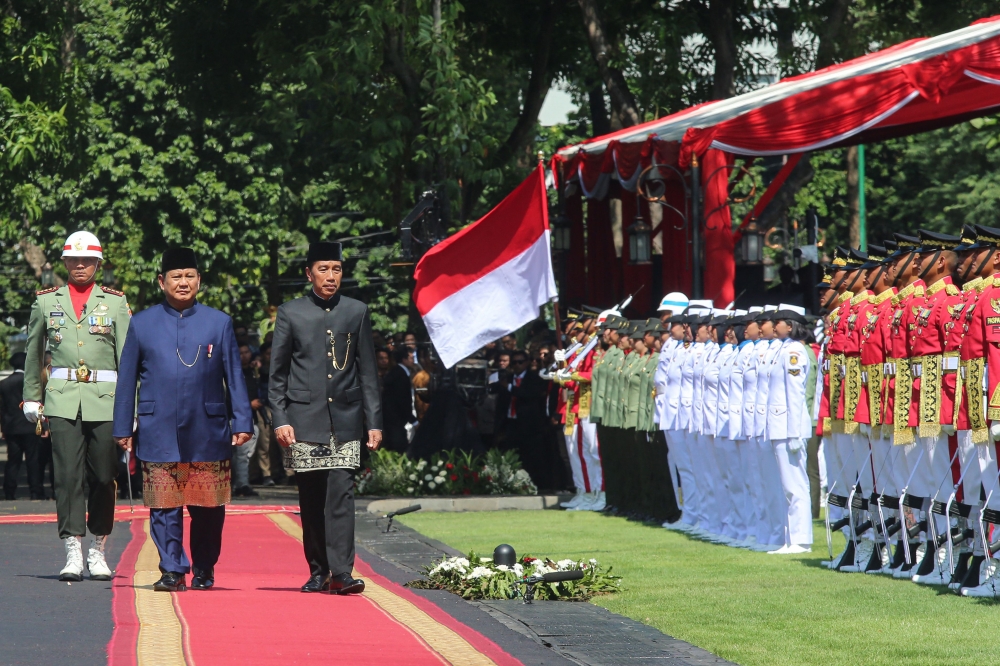 Indonesia's newly sworn-in Prabowo Subianto (L) and his predecessor Joko Widodo (2L) review the troops during the presidential inauguration ceremony at the Presidential Palace in Jakarta on October 20, 2024. (Photo by Gyl Batara / AFP)
 