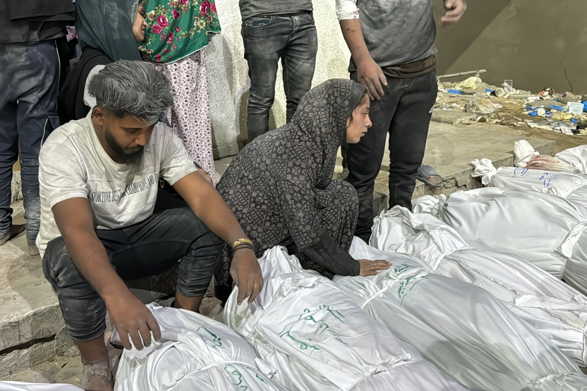 Palestinians mourn over the covered bodies of relatives, killed in an Israeli airstrike, outside the Kamal Adwan Hospital in Beit Lahia, in the northern Gaza Strip on October 19, 2024. Photo by Islam AHMED / AFP.
