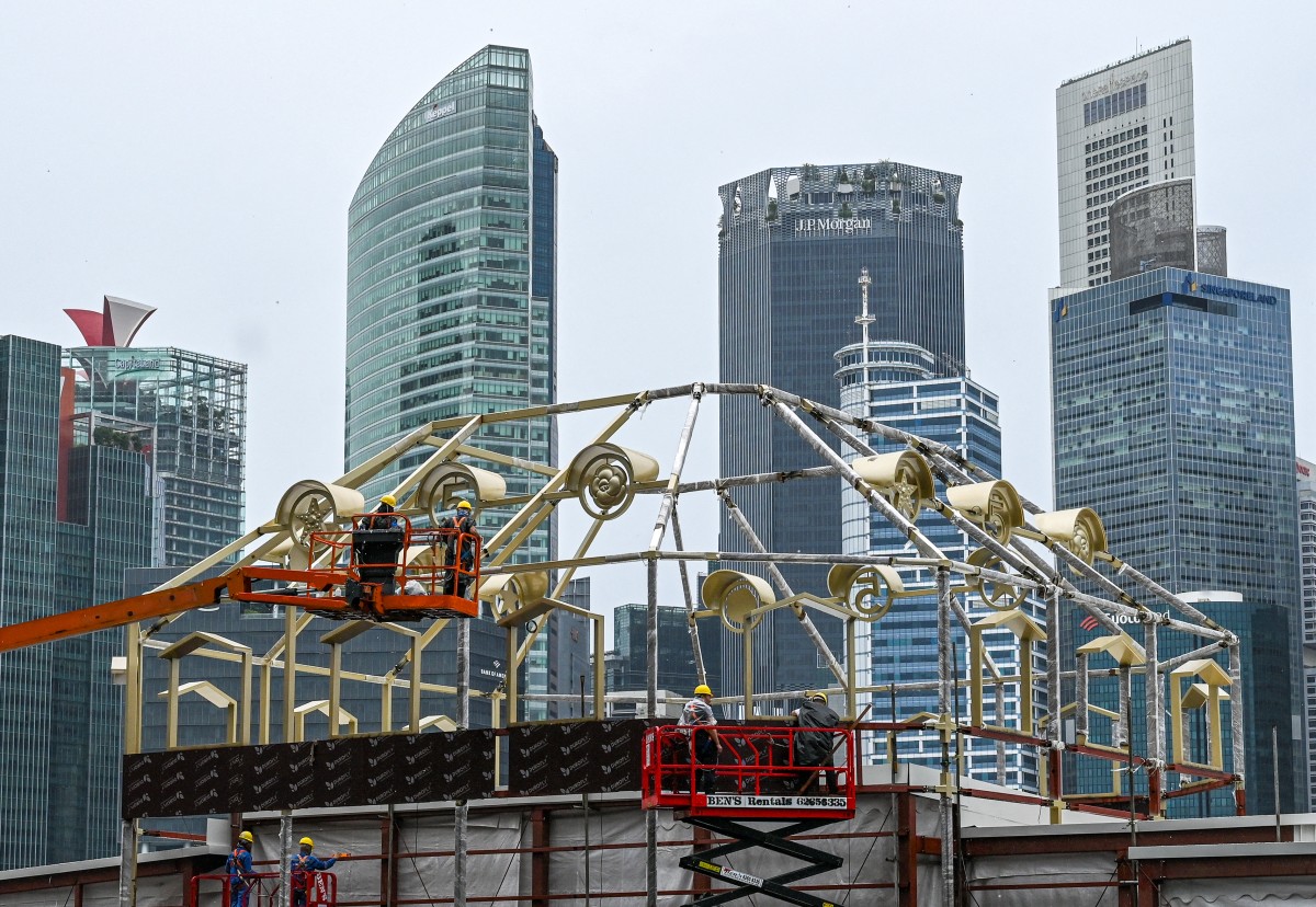 Photo used only for demonstration purposes. Workers stand on lifting platforms as they assemble the structure of a temporary construction near the financial business district in Singapore on October 14, 2024. Photo by Roslan RAHMAN / AFP.
