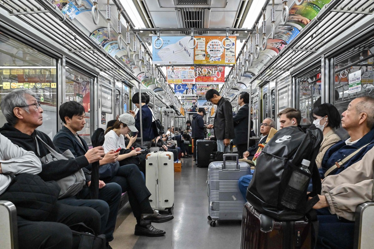 People ride on the Tokyo Metro underground system in central Tokyo on October 21, 2024. (Photo by Richard A. Brooks / AFP)
