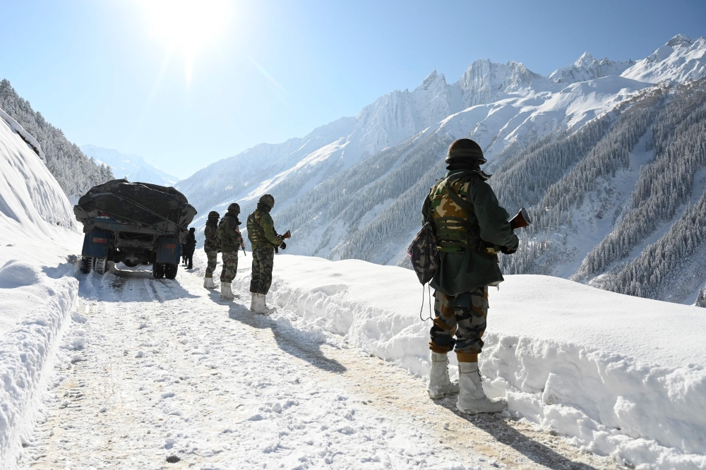 File: Indian army soldiers walk along a road near Zojila mountain pass that connects Srinagar to the union territory of Ladakh, bordering China on February 28, 2021. (Photo by Tauseef Mustafa / AFP)