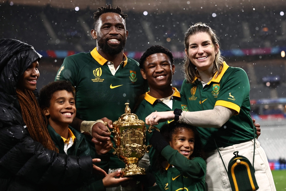 (Files) South Africa's flanker and captain Siya Kolisi (3rd L) and his wife Rachel Kolisi (R) pose for a photo with their family after South Africa won the France 2023 Rugby World Cup Final match  on October 28, 2023. (Photo by Anne-Christine Poujoulat / AFP)