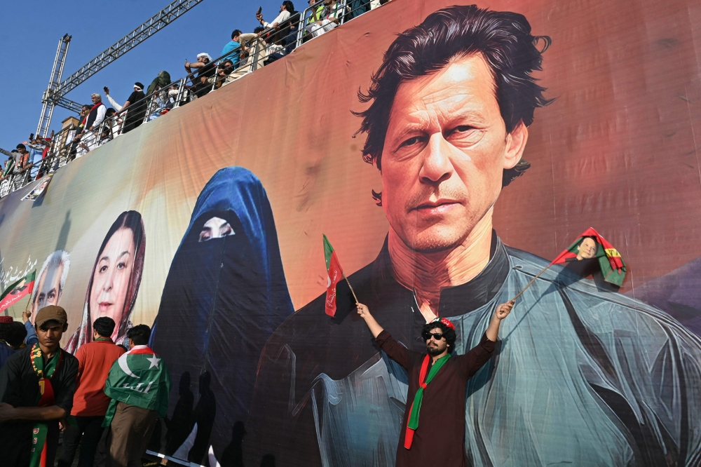 File: A tarp image of former Prime Minister Imran Khan and wife Bushra Bibi during a rally in Islamabad on September 8, 2024. (Photo by Farooq Naeem / AFP)

