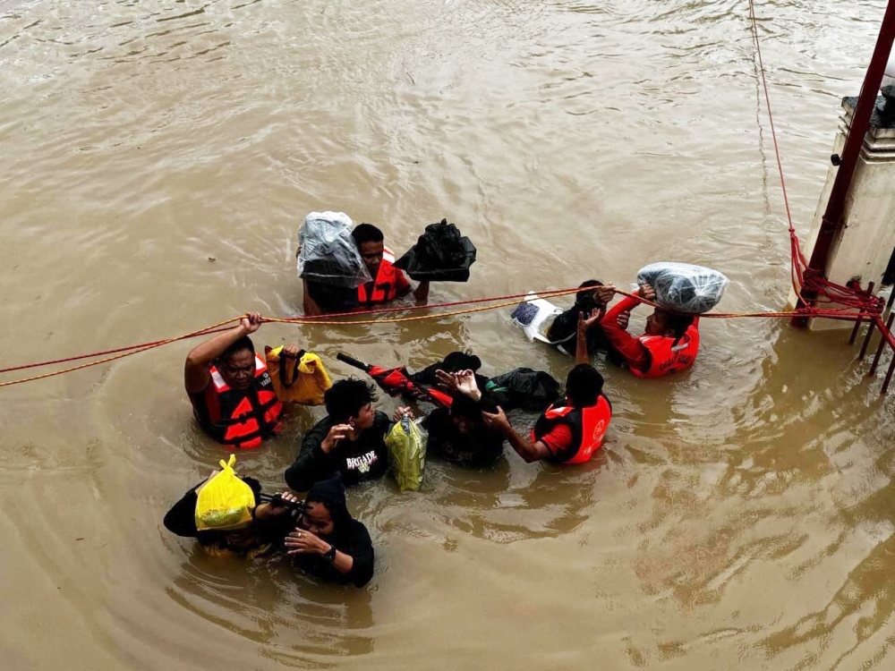 In this handout photo from the Philippine Coast Guard (PCG) taken and received on October 24, 2024, rescuers conduct a rescue operations in a flooded area in Nabua, Camarines Sur, due to Tropical Storm Trami. (Photo by Handout / Philippine Coast Guard (PCG) / AFP)