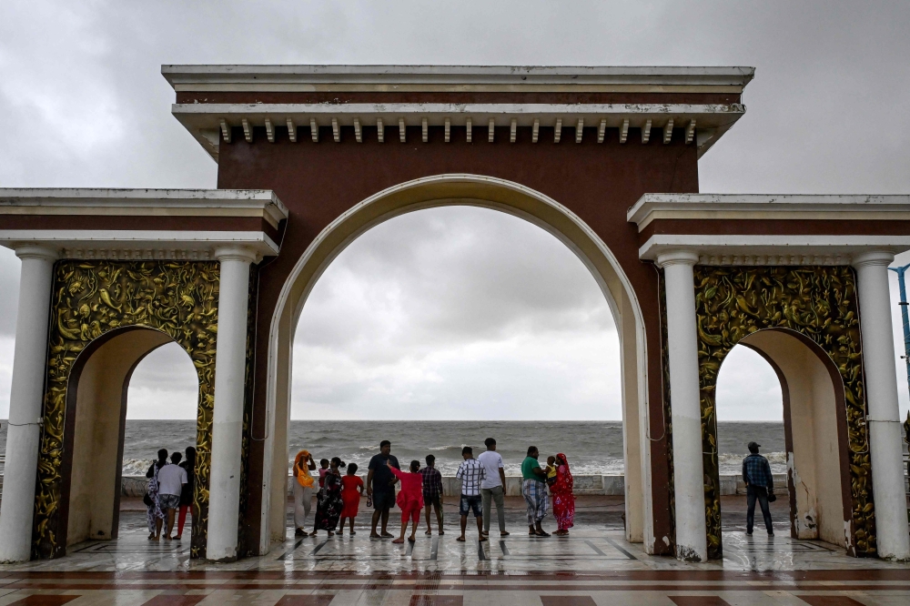 Tourists walk along a beach as dark clouds loom over the sky in Digha around 220 km southwest of Kolkata, on October 25, 2024, after cyclone Dana hits the coasts of India's West Bengal and Odisha states. Photo by DIBYANGSHU SARKAR / AFP