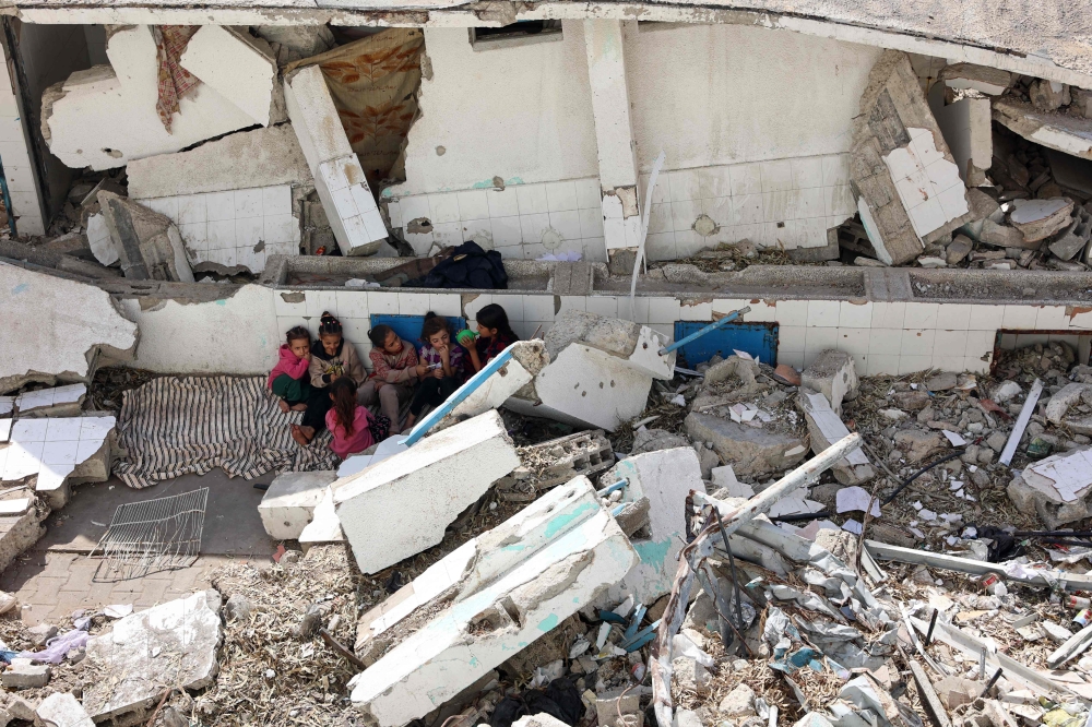 Displaced Palestinian children sit amid the rubble of a destroyed building in the Nasser district of Gaza City, in the northern Gaza Strip on October 25, 2024. (Photo by Omar Al-Qattaa / AFP)