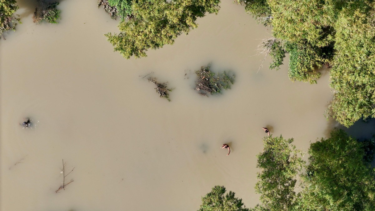 This picture shows an aerial view of people wading through a flooded area as they search for the body of a villager in Tuguegarao, Cagayan province, north of Manila on October 26, 2024. Photo by John DIMAIN / AFP