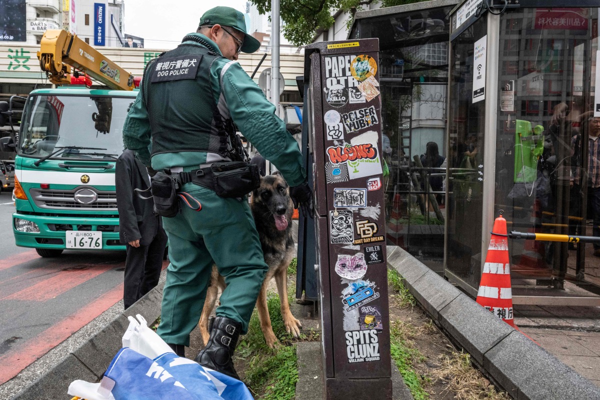 A police officer patrols with a police dog before an election campaign speech by Yoshihiko Noda, leader of the Constitutional Democratic Party (CDP), in front of Shibuya station in Tokyo on October 26, 2024. Photo by Yuichi YAMAZAKI / AFP