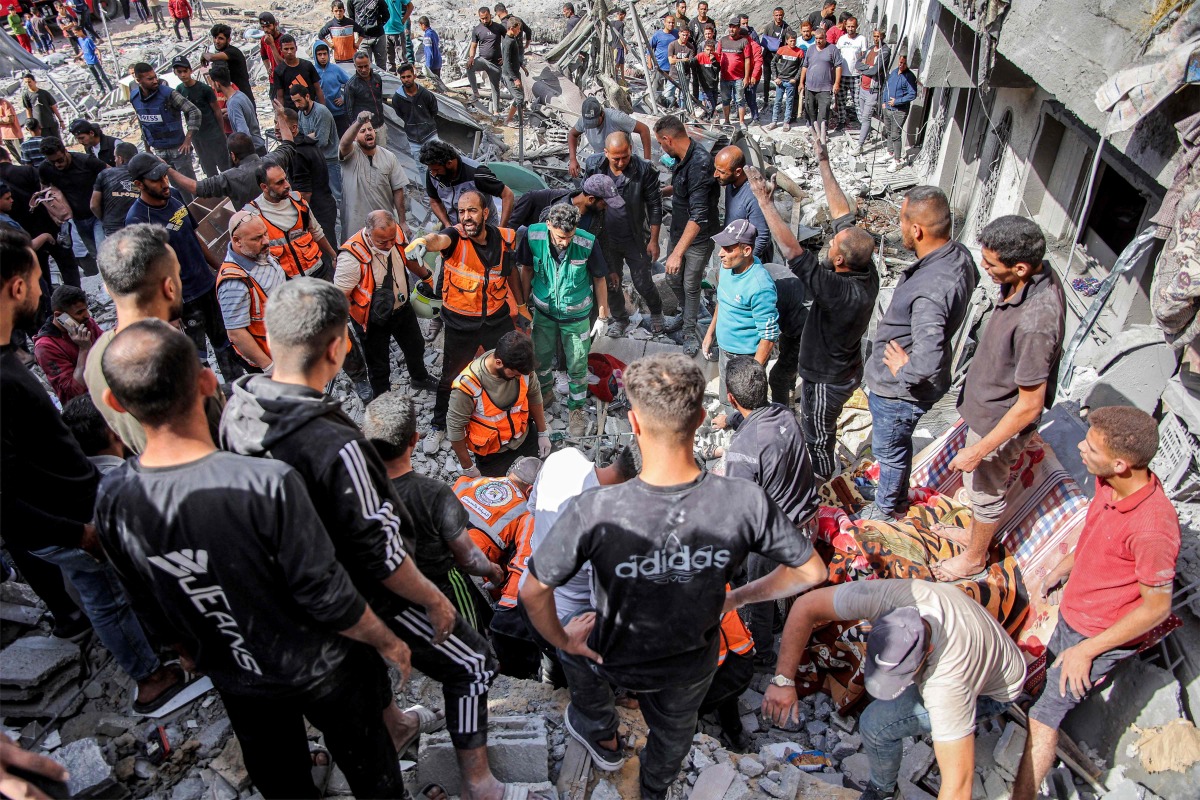 Palestinian civil defence members search for survivors and victims through the rubble following Israeli bombardment on the four-storey Muqat family house in the Zarqa neighbourhood in the north of Gaza City on October 26, 2024 amid the ongoing war in the Palestinian territory between Israel and Hamas. (Photo by Omar AL-QATTAA / AFP)
