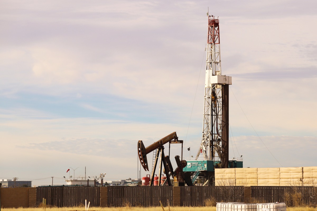 A pumpjack and drilling rig in Midland, Texas.