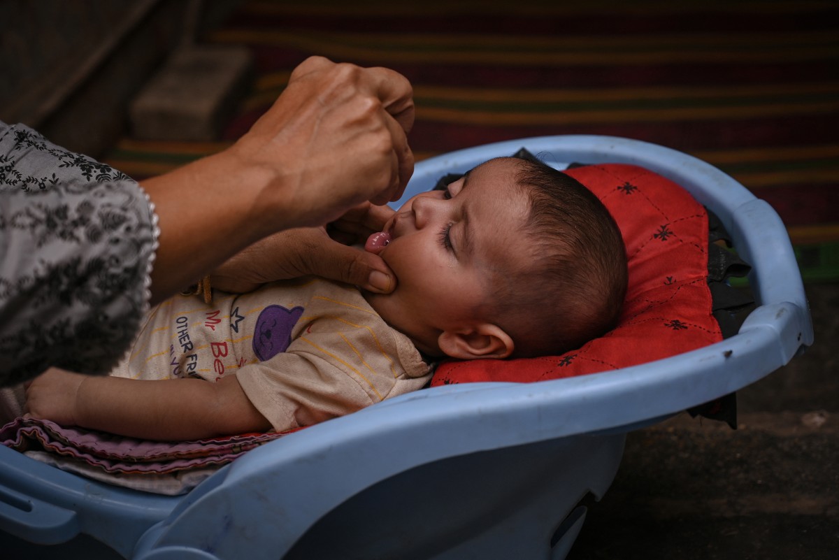 A health worker administers polio drops to a child during a door-to-door vaccination campaign in Karachi on October 28, 2024. Photo by Rizwan TABASSUM / AFP.
