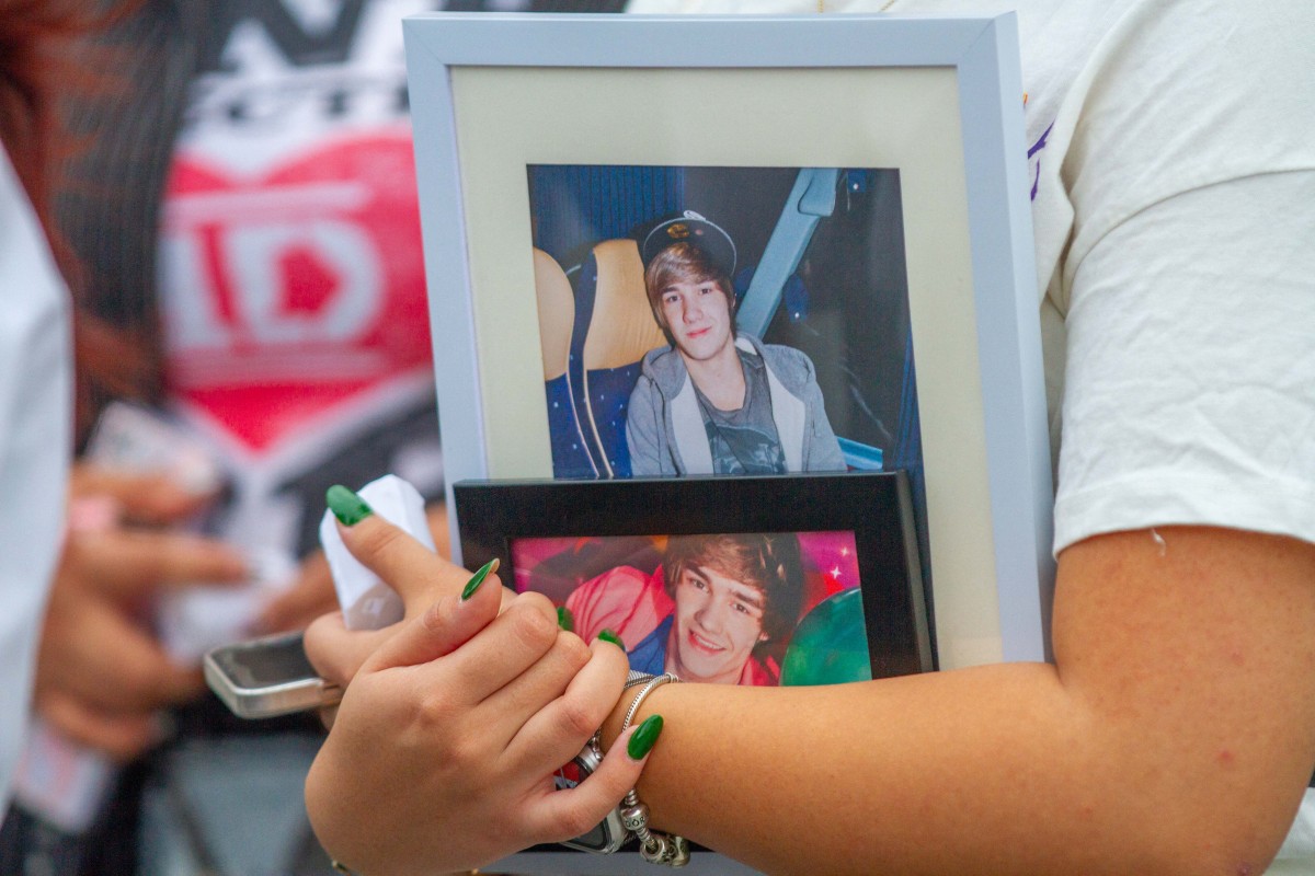 A fan of late British singer Liam Payne hold pictures of him as she pays respects on the esplanade of the Monterrey macroplaza, on October 20, 2024. Photo by Julio Cesar AGUILAR / AFP