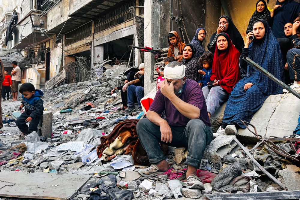 An injured man reacts while sitting on the rubble of a building hit by an Israeli strike in Beit Lahia, in the northern Gaza Strip, on October 29, 2024. Photo by AFP