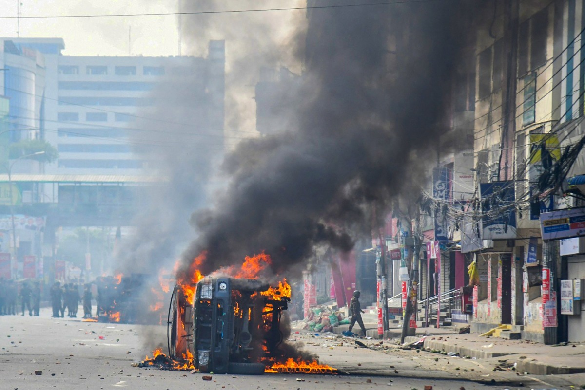 Flames engulf a military vehicle after clashes between protesters and the police in Mirpur on October 31, 2024. Bangladeshi garment workers furious at job layoffs in the economically vital sector clashed with police and soldiers on October 31, with two teenagers shot and wounded, officers said. (Photo by Md. Naimur Rahman / AFP)