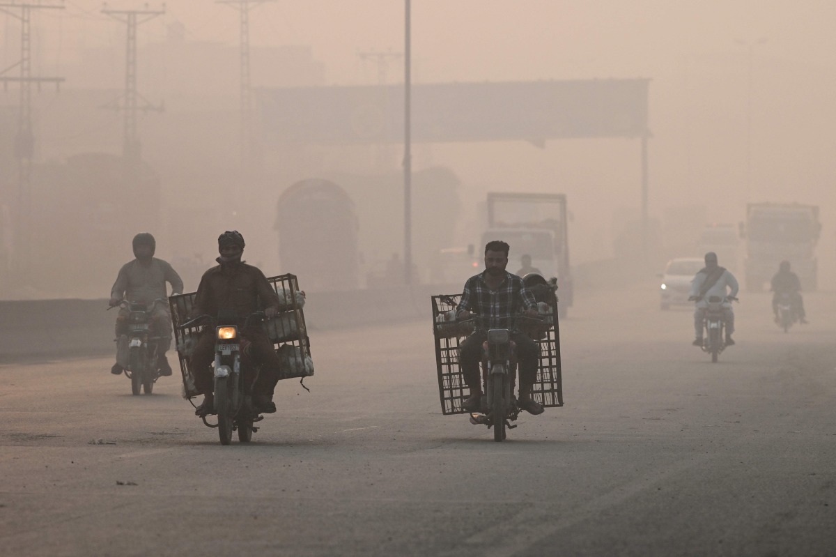 Commuters make their way amid smog in Lahore on November 2, 2024. (Photo by Arif ALI / AFP)
