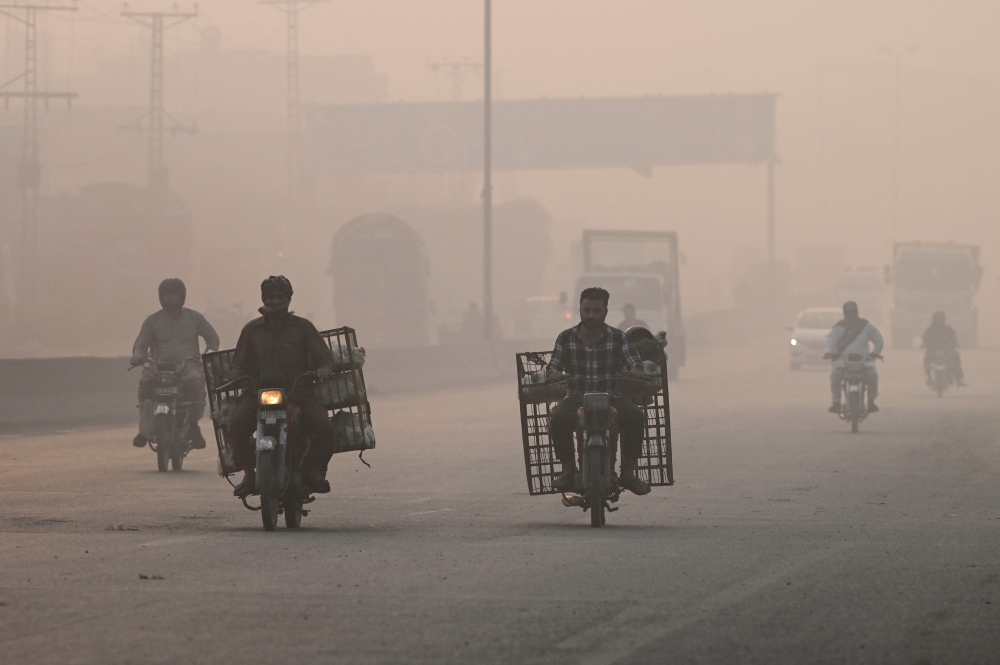 Commuters make their way amid smog in Lahore on November 2, 2024. (Photo by Arif Ali / AFP)