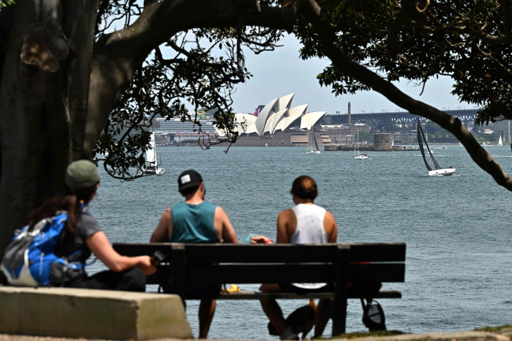 Visitors spend their morning under a large tree at Bradleys Head in Sydney, overlooking the Opera House on November 3, 2024. (Photo by Saeed Khan / AFP)
 