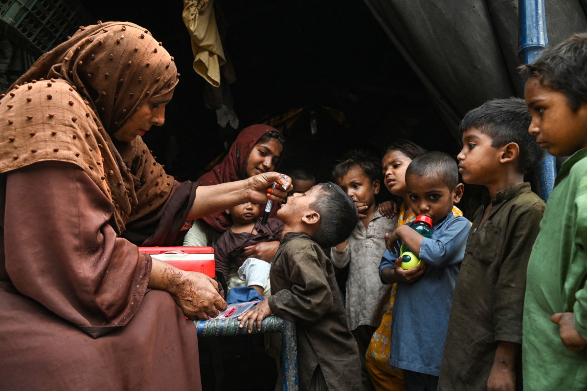 Health workers administer polio drops to children during a door-to-door vaccination campaign in Lahore on October 28, 2024. Photo by Arif ALI / AFP.