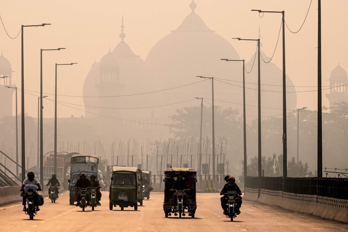 Commuters ride along a street engulfed in smog, in Lahore on November 5, 2024. Photo by Arif ALI / AFP