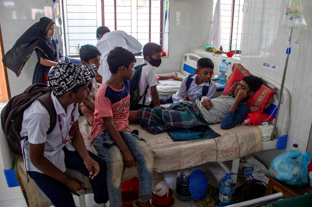 In this photograph taken on November 4, 2024, Naeem (R), a schoolboy, gets treatment for dengue as his friends visit him inside a children's ward in Shaheed Suhrawardy Medical College and Hospital in Dhaka. Photo by Abdul Goni / AFP