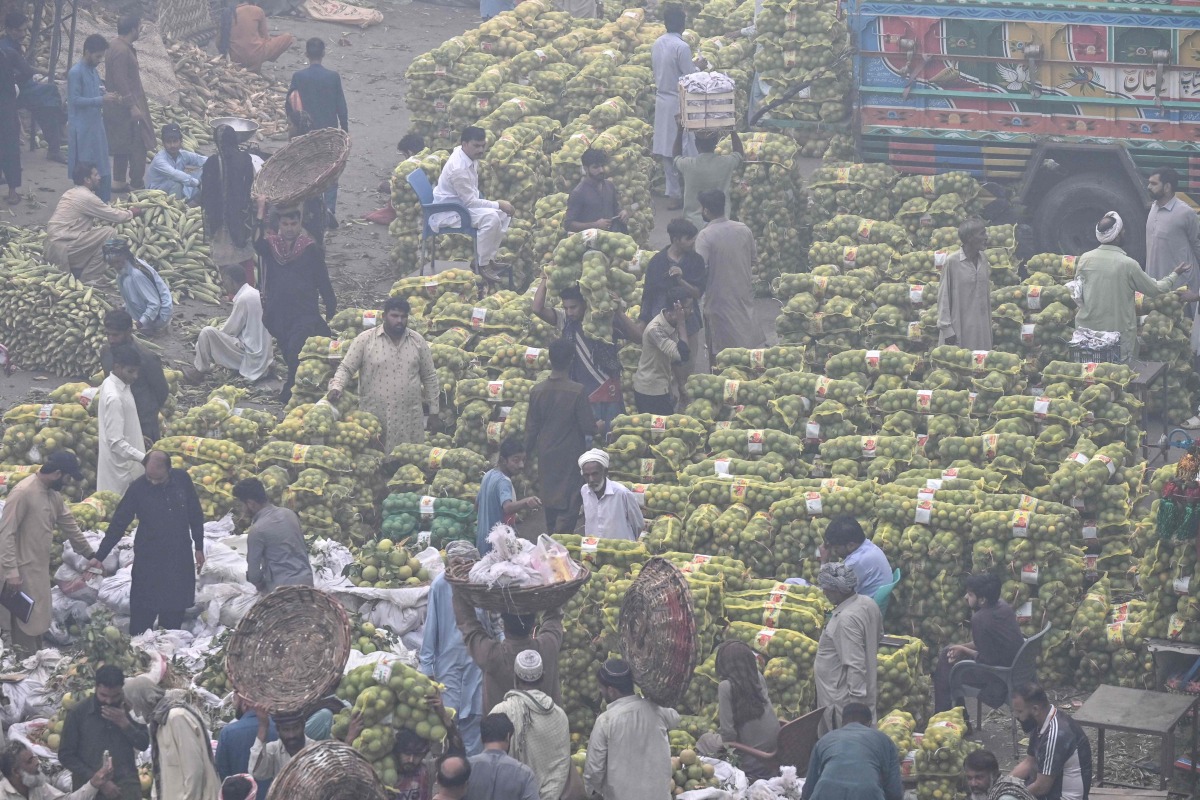 Traders and customers crowd at a wholesale fruit market engulfed in smog in Lahore on November 8, 2024. Photo by Arif ALI / AFP