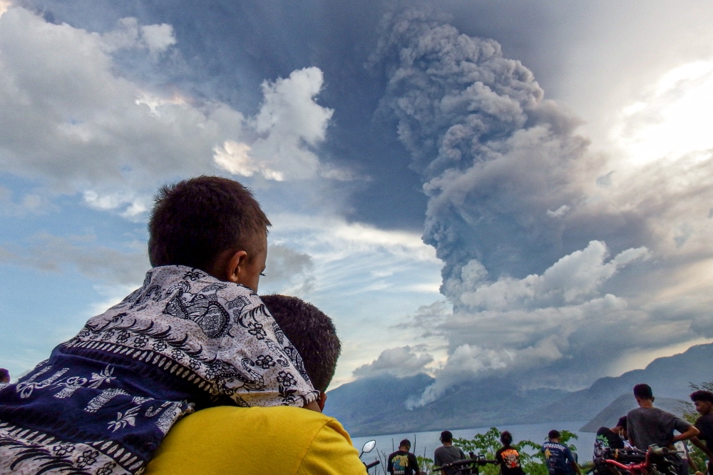 Residents watch the eruption of Mount Lewotobi Laki Laki from Eputobi village in Titihena, East Nusa Tenggara, on November 8, 2024. (Photo by Bayu Ismoyo and Arnold Welianto / AFP)