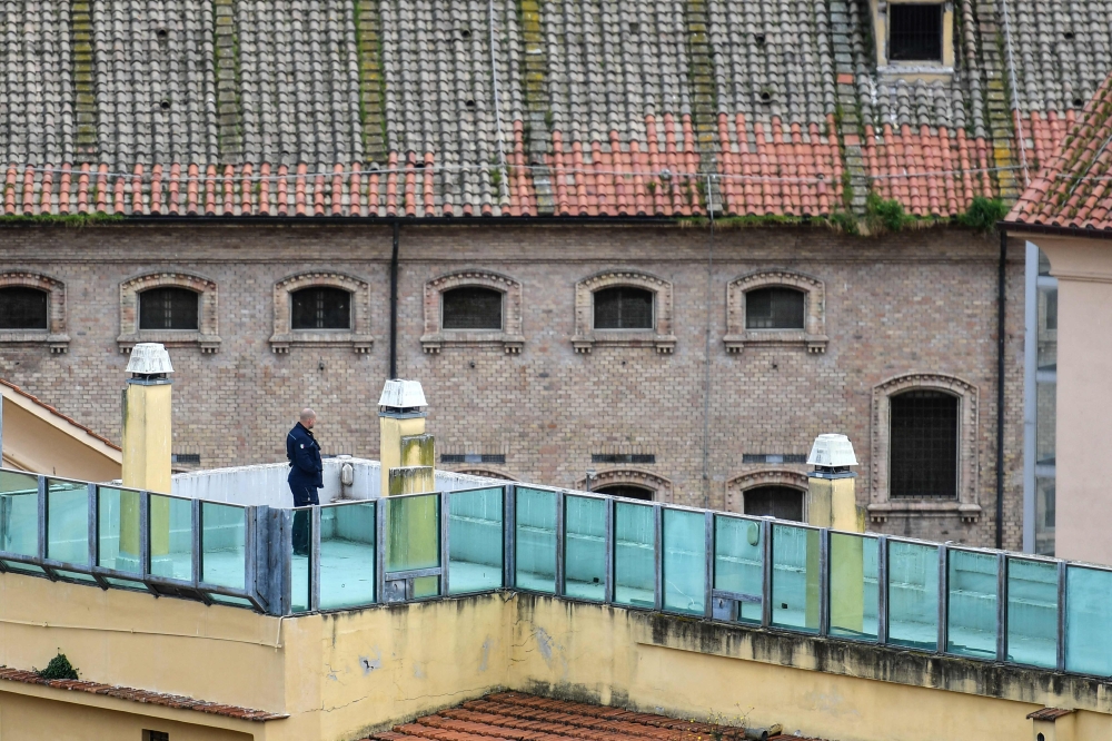 (Files) A prison guard patrols a prison building's terrace overlooking the prison's wings, after smoke billowed from a rooftop of the Regina Coeli prison in central Rome on March 9, 2020. (Photo by Alberto Pizzoli / AFP)