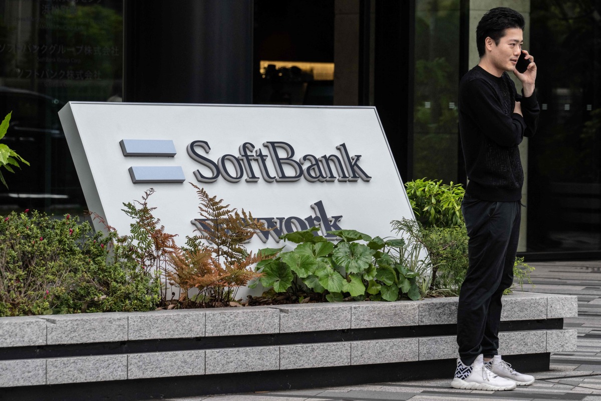 (FILES) This file photo taken on May 2, 2024 shows a man talking on his phone outside the headquarters for Japanese company SoftBank Group in Tokyo. (Photo by Yuichi YAMAZAKI / AFP)
